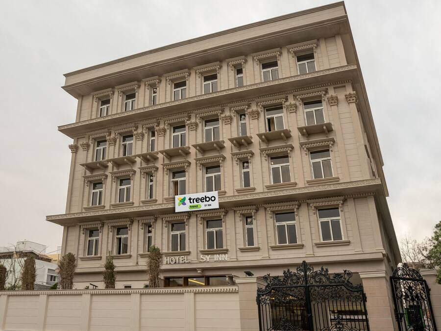 A multi-story hotel with a classical architectural style, featuring a prominent sign for 'Treebo Trend SY Inn'.