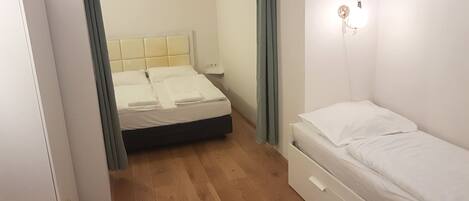 A small, compact bedroom with a bed, a nightstand, and a dresser.