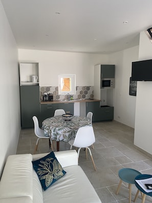 A compact living space with a dining area, kitchenette, and a sofa with a decorative pillow.