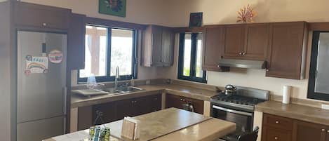 A kitchen with wooden cabinets, a stainless steel refrigerator, a stove, and a sink.