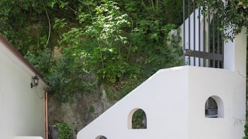 Um edifício branco com um pátio de azulejos e uma escadaria que leva a uma porta.