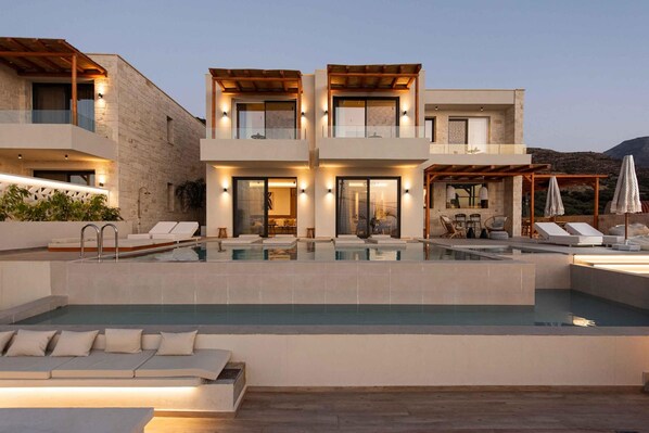 A modern two-story house with a swimming pool, outdoor seating, and a pergola.