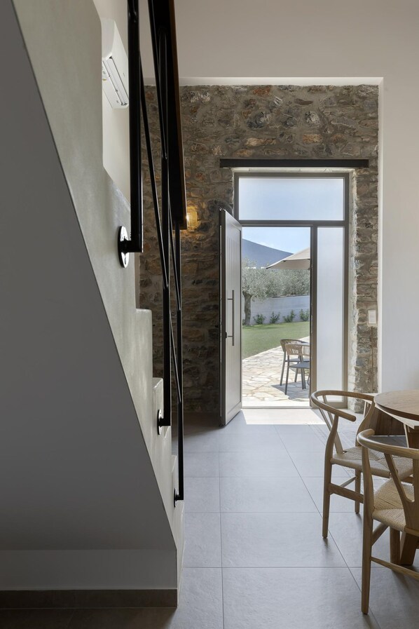 Un interior moderno con una pared de piedra, una mesa de comedor de madera y una escalera.