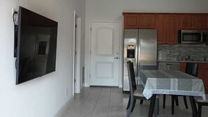 A modern kitchen with a built-in microwave, stainless steel refrigerator, and wooden cabinets.