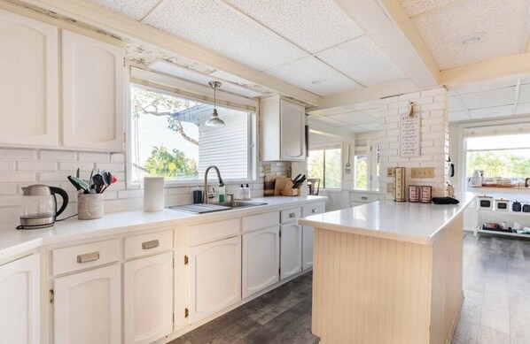 A kitchen with white cabinetry, a large island, and a window providing natural light. - Beautiful Country Home located outside of Jacksonville with pool!  (Central Point)