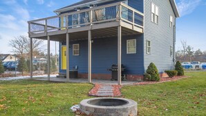 A two-story building with a covered porch and a fire pit in the yard.