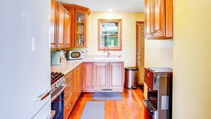 A compact kitchen with wooden cabinets, a microwave, a sink, and a stainless steel dishwasher.