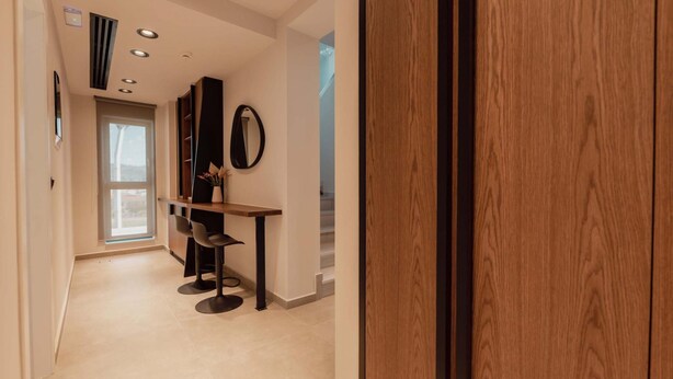 A modern hallway with a wooden door, a small table with chairs, and a mirror on the wall. - City Moments Penthouse I Close to Everything (Chania)