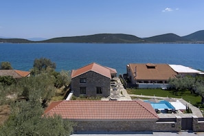 A coastal property with stone buildings, a swimming pool, and a view of the sea.