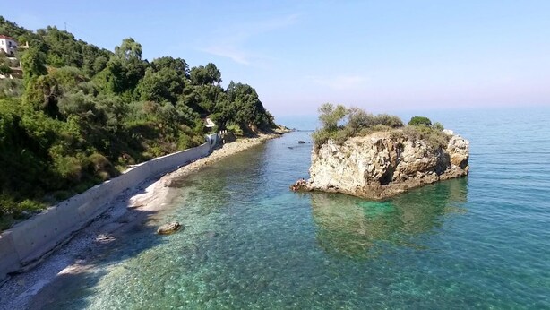 Une route côtière bordée d’une falaise rocheuse et d’une eau cristalline.
