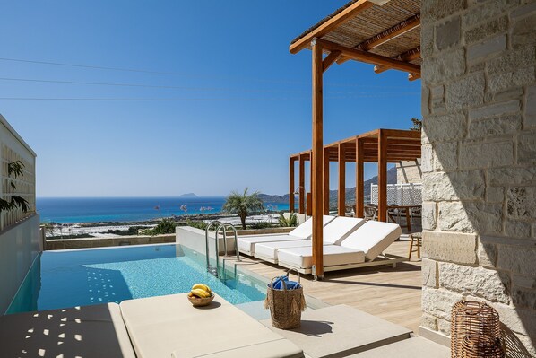 A poolside area with lounge chairs, a wicker basket, and a view of the sea. - Villa Domenica I Free car Free Heated Pool (Kissamos)