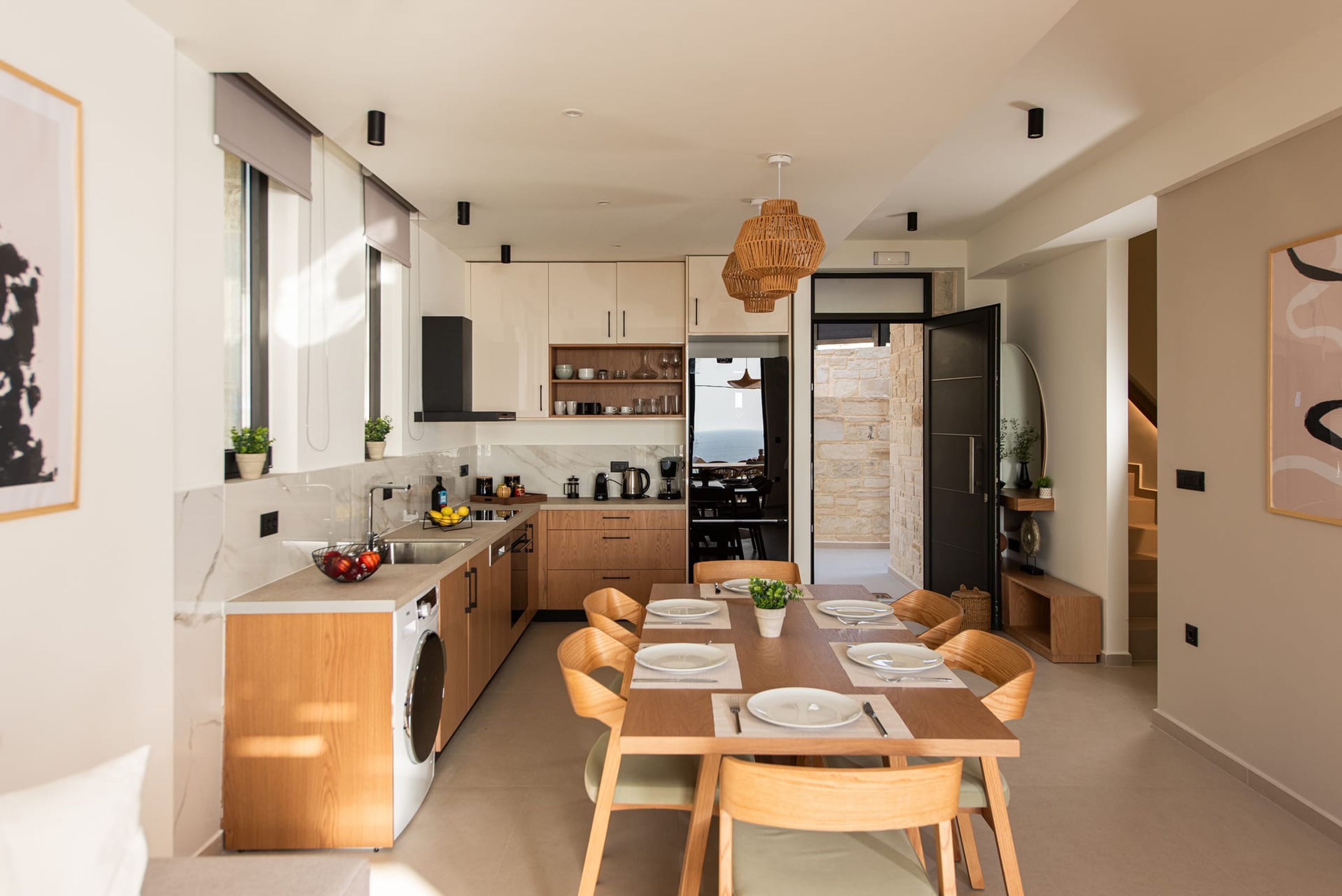 Eine moderne Küche mit Holzschränken, einem Esstisch für sechs Personen und einem großen Fenster mit Tageslicht.