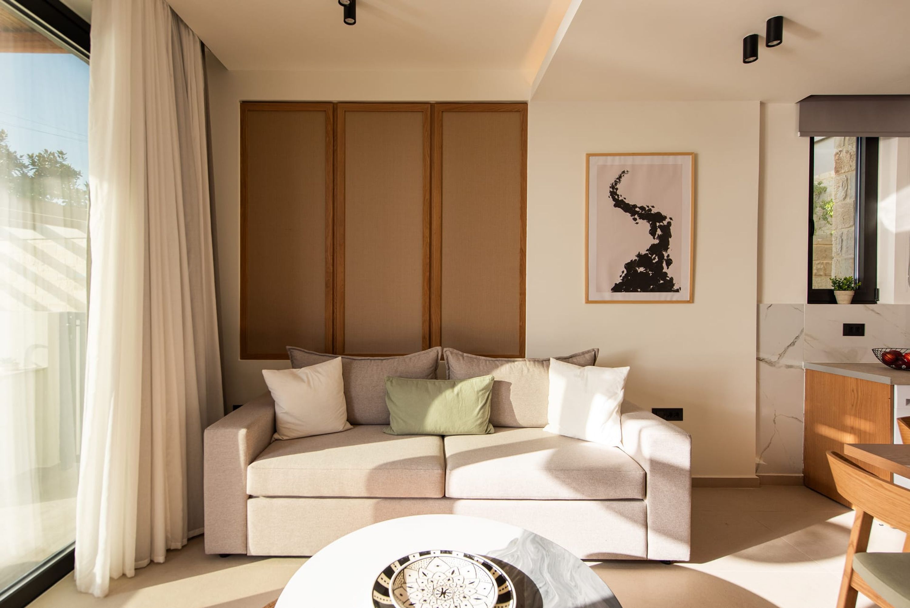 A modern living room with a sofa, a coffee table, and a painting on the wall.