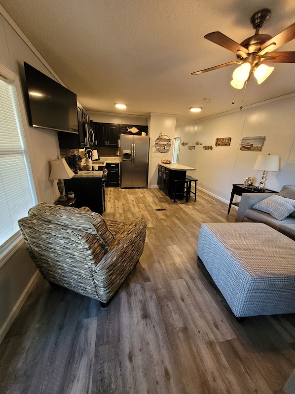 A compact living space with a kitchen, a dining area, and a seating area with a sofa and a chair. - CROSSROADS TO PICKWICK THE PORCH  (Iuka)