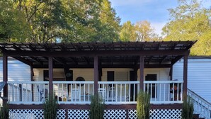 Ein Haus mit überdachter Veranda, weißen Geländern und einem kleinen Garten.