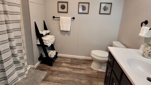 Ein Badezimmer mit Dusche, Toilette, Waschbecken und einem Handtuchhalter mit Handtüchern.