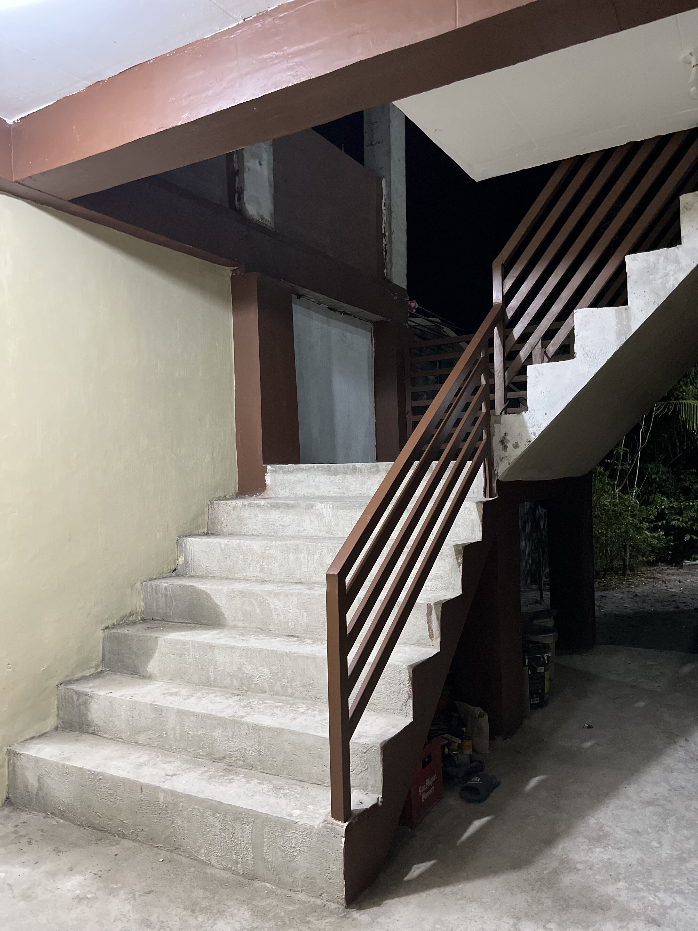 A concrete staircase with a brown handrail leading to an upper level.