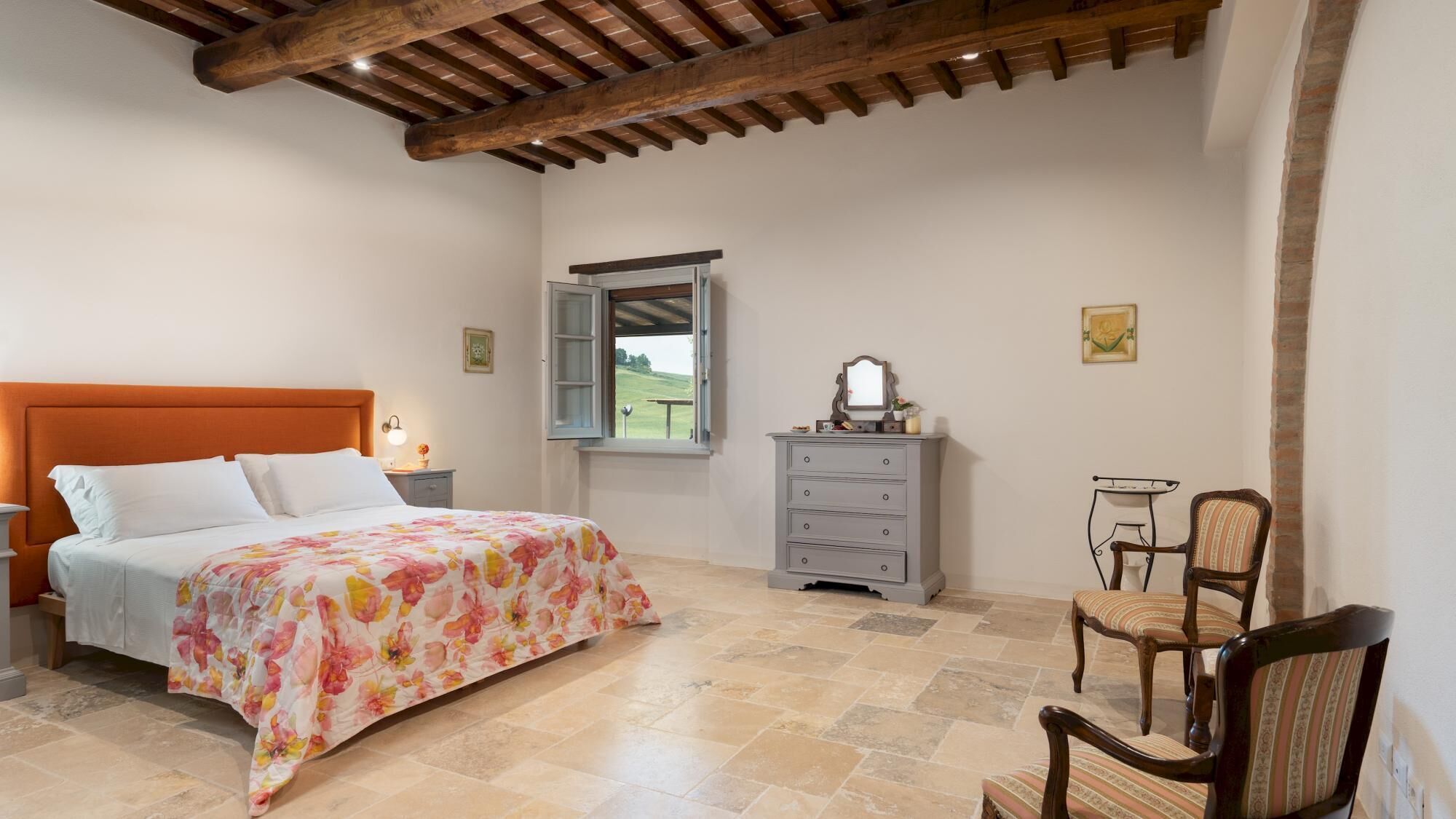 A bedroom with a bed, a dresser, a chair, and a window with an open shutter.