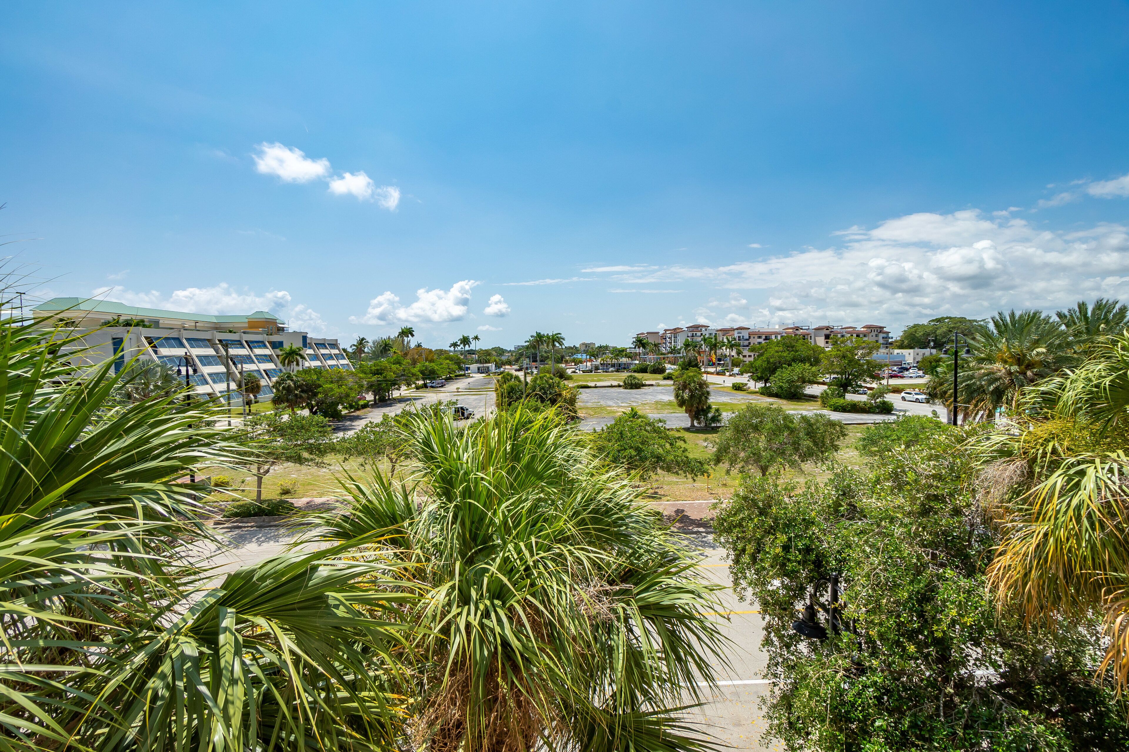 A hotel with a modern design, featuring a parking lot and lush greenery.