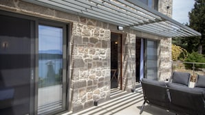 Un bâtiment en pierre doté de grandes fenêtres et d’un patio couvert.