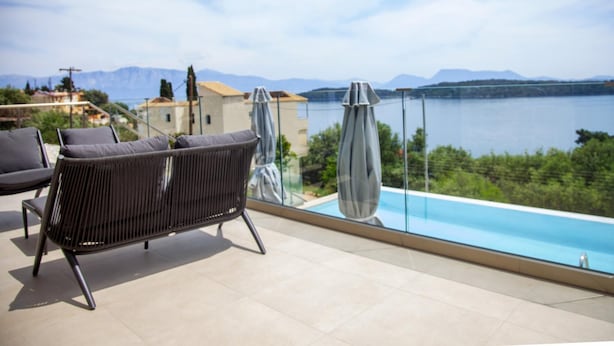 Une terrasse avec une piscine, des chaises longues et une vue sur un lac et des montagnes.