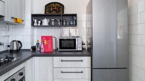 A modern kitchen with white cabinetry, a stainless steel refrigerator, a microwave, and a gas stove. - Appartamento Ibisco by Wonderful Italy (Bologna)