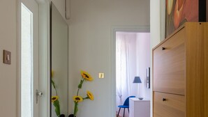A hallway with a tiled floor, a wooden dresser, a desk with a lamp, and a chair. - Appartamento Ibisco by Wonderful Italy (Bologna)