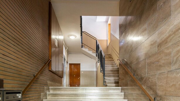 A staircase with a wooden handrail and beige steps leading to a door at the top. - Appartamento Ibisco by Wonderful Italy (Bologna)