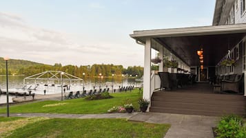 Un bâtiment situé au bord du lac, doté d’un espace extérieur couvert avec des sièges, d’un quai et d’une vue sur le lac.