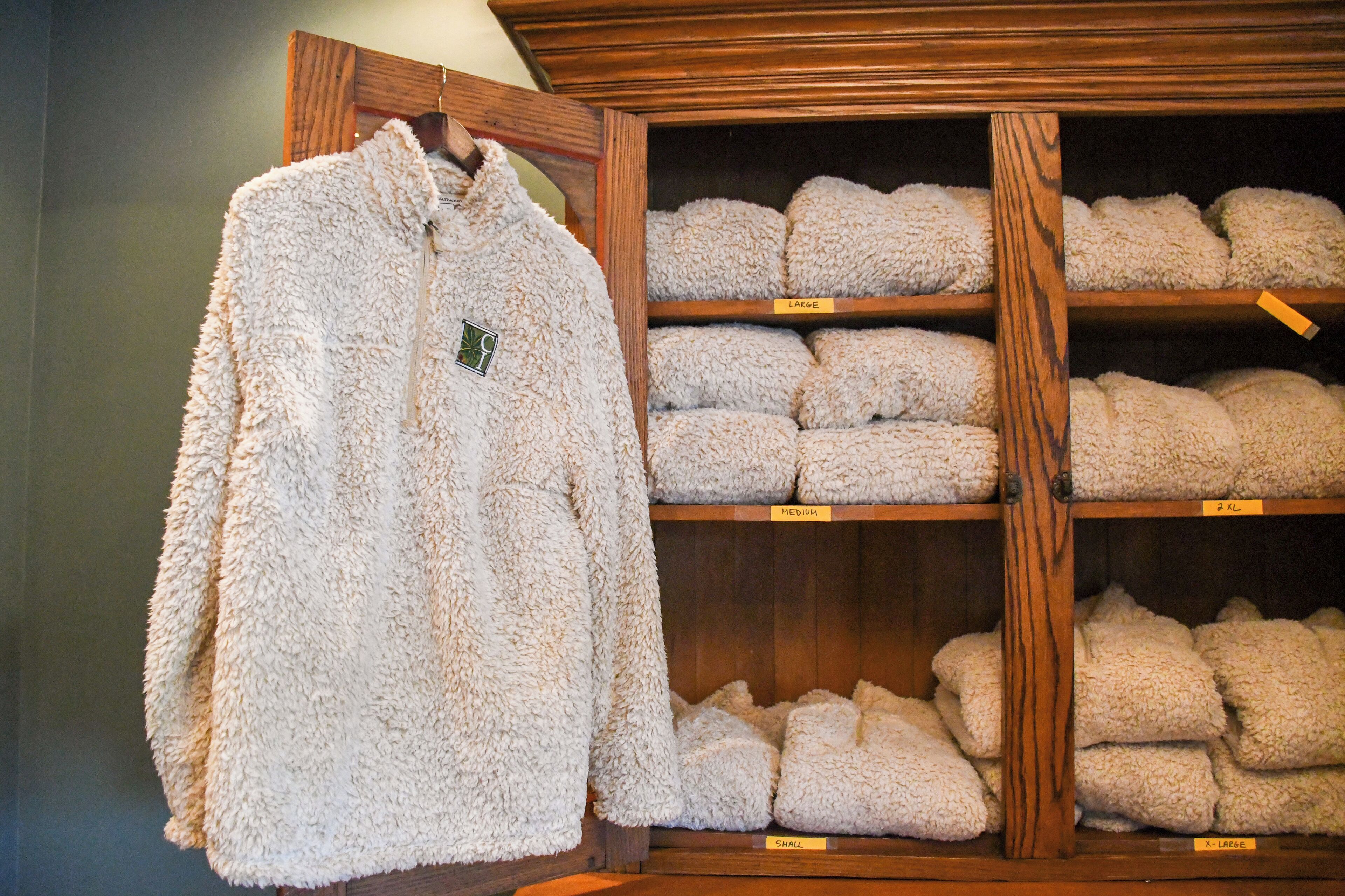 A store with shelves labeled 'Small,' 'Medium,' and 'Large' containing various sizes of fluffy, white blankets.
