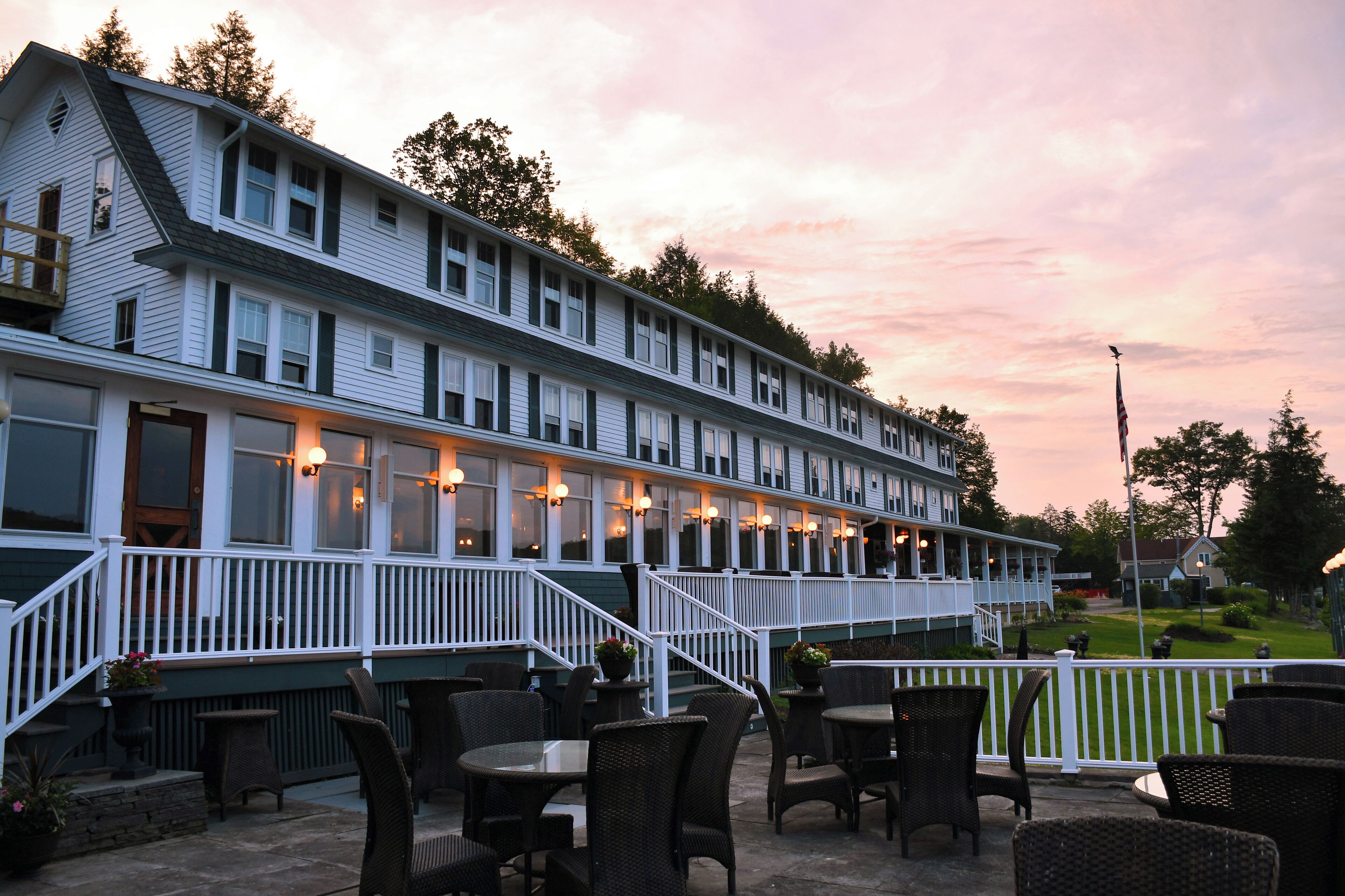 A two-story building with a covered patio area featuring outdoor seating and a staircase leading to the upper level.