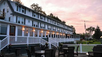 A two-story building with a covered patio area featuring outdoor seating and a staircase leading to the upper level.