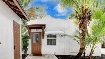 A white stucco house with a brown door and a small porch.