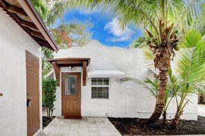 Una casa in stucco bianco con una porta marrone e un piccolo portico.