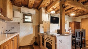 Een keuken met houten kastjes, een inbouwoven en een betegelde spatwand.