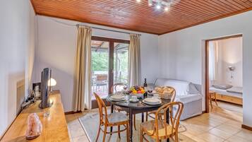 Una habitación acogedora con techo de madera, una mesa de comedor con sillas, una cama y un televisor.