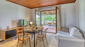A dining area with a table set for four, a sofa, a TV, and a view of the outdoors.