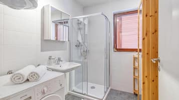 Ein modernes Badezimmer mit Duschkabine aus Glas, einem Waschbecken und einer Waschmaschine.