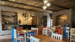 A rustic restaurant interior with brick walls, wooden tables, and chairs. - Hacienda Santa Ana Lodging (Guamote)