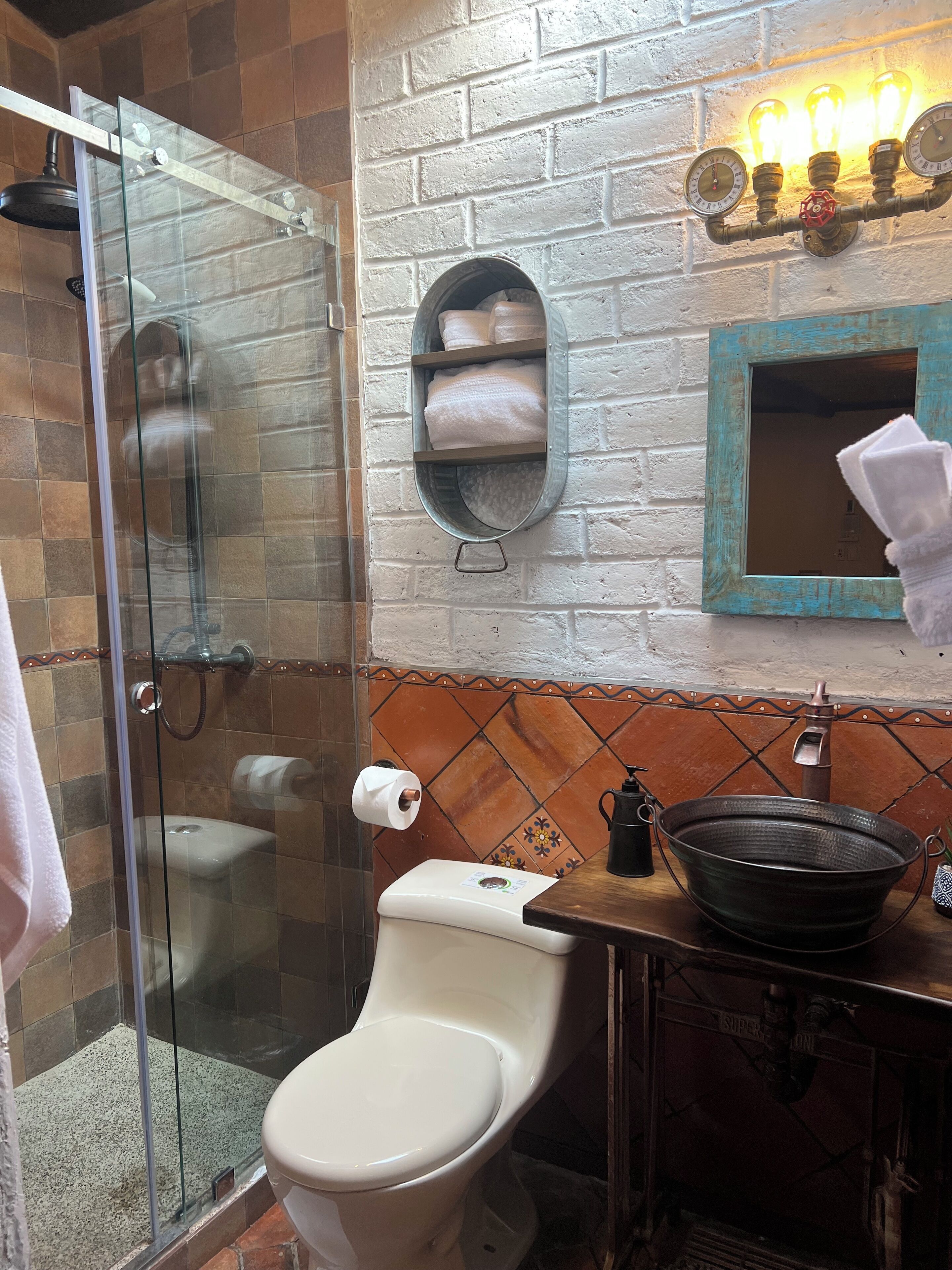 Un baño con ducha de vidrio, inodoro, lavabo y toallero.