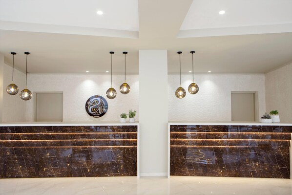 A reception desk with marble countertops, pendant lighting, and a wall-mounted logo. - Ajul Luxury Hotel & Spa Resort Registry Collection (Kassandra)