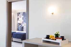 A hotel room with a bed, a bedside table with breakfast items, a wall-mounted light, and a floral painting. - Ajul Luxury Hotel & Spa Resort Registry Collection (Kassandra)