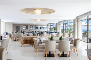 A modern hotel lobby with a spacious seating area, large windows, and a view of the sea. - Ajul Luxury Hotel & Spa Resort Registry Collection (Kassandra)