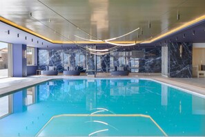 A modern indoor swimming pool with a clear blue water surface, marble walls, and contemporary lighting fixtures. - Ajul Luxury Hotel & Spa Resort Registry Collection (Kassandra)