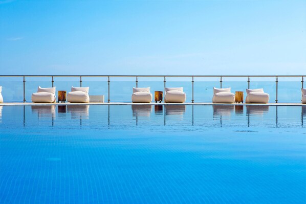 A poolside area with lounge chairs and a glass railing.
