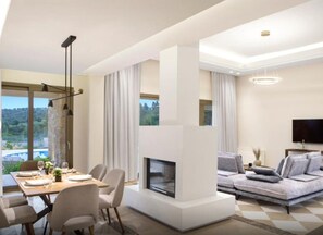 A modern living room with a fireplace, dining area, and a sofa. - Ajul Luxury Hotel & Spa Resort Registry Collection (Kassandra)