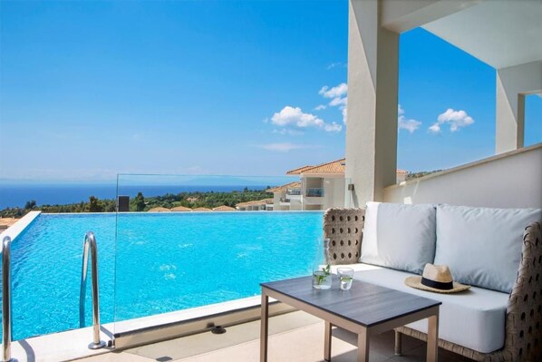 A balcony with a pool, a sofa, and a table. - Ajul Luxury Hotel & Spa Resort Registry Collection (Kassandra)
