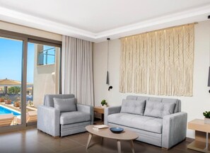 A modern living room with a sofa, armchairs, a coffee table, and a view of a swimming pool. - Ajul Luxury Hotel & Spa Resort Registry Collection (Kassandra)