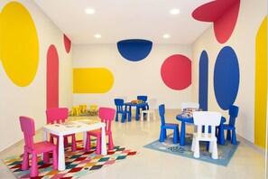 A children's playroom with colorful chairs and tables, geometric wall decorations, and a patterned rug. - Ajul Luxury Hotel & Spa Resort Registry Collection (Kassandra)