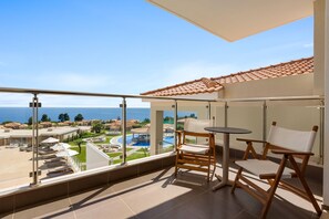 A balcony with a view of a pool and resort area, a table, and two chairs. - Ajul Luxury Hotel & Spa Resort Registry Collection (Kassandra)